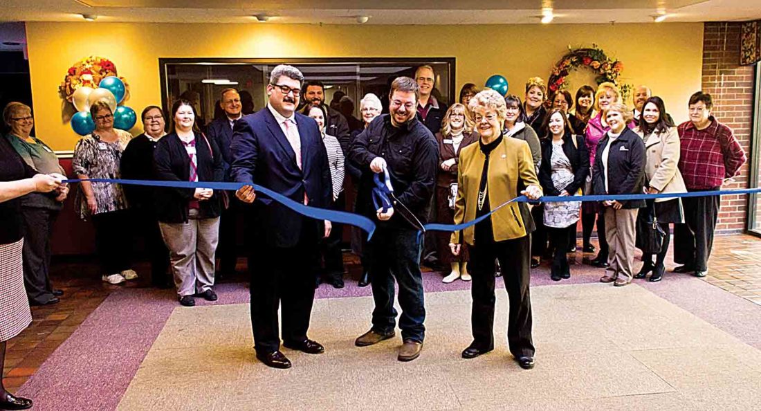 Jonny participating in a ribbon-cutting ceremony with a group of attendees